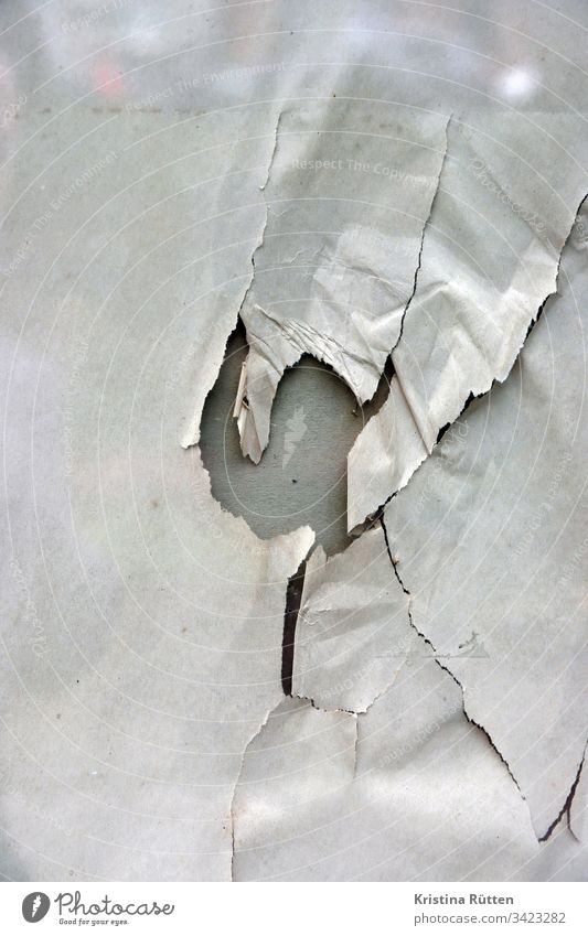 papier mit loch hinter glasscheibe packpapier gerissen kaputt fenster schaufenster spiegelung struktur textur hintergrund material oberfläche zerstört abstrakt