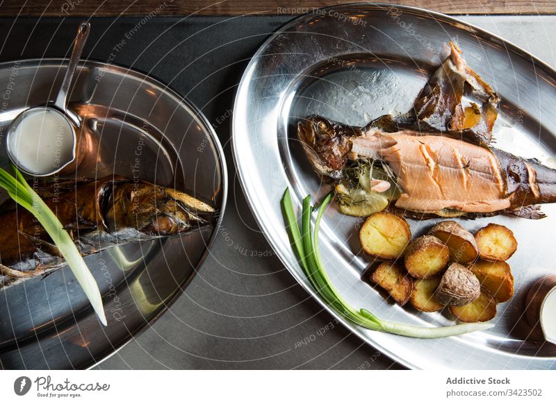 Gebratener Fisch und Kartoffeln mit Sahnesoße und frischer Schalotte Grillrost Restaurant Teller Frühlingszwiebel Saucen Lebensmittel Mahlzeit lecker
