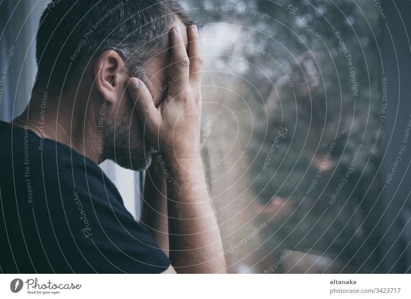 Porträt eines traurigen Mannes, der in der Nähe eines Fensters steht Traurigkeit Verlust Problematik deprimiert ernst Angst Trauer Frustration unglücklich