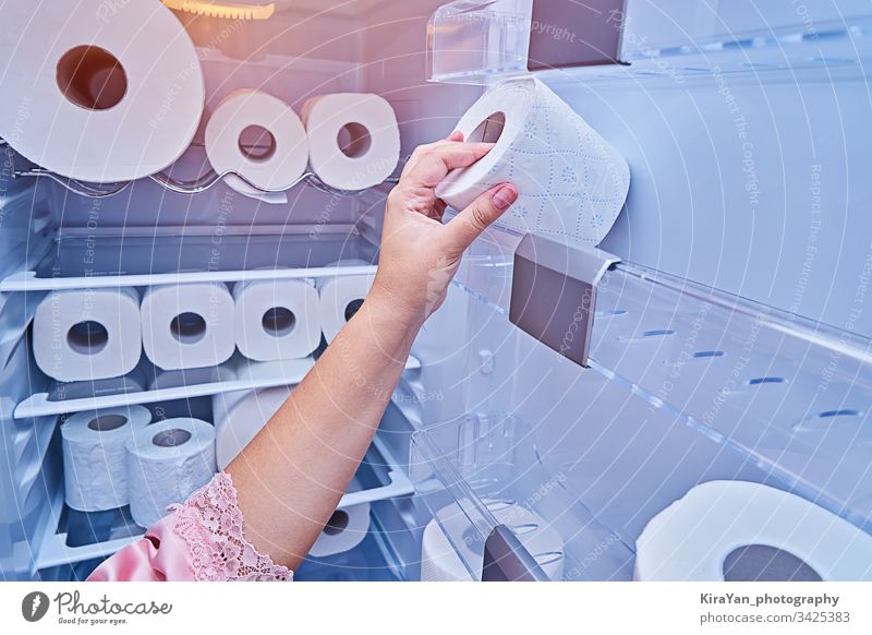 Weibliche Hand nimmt eine Rolle Toilettenpapier von der Kühlschranktür Coronavirus covid-19 Frau nehmen rollen Papier Küche Haushalt Streich Gewebe heimwärts