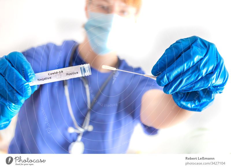 eine Ärztin hält ein Abstrichröhrchen mit Coronavirus in der Hand Tupfer-Röhrchen Arzt covid-19 Mundschutz Beweis positiv negativ 2019-ncov krankheitserregend