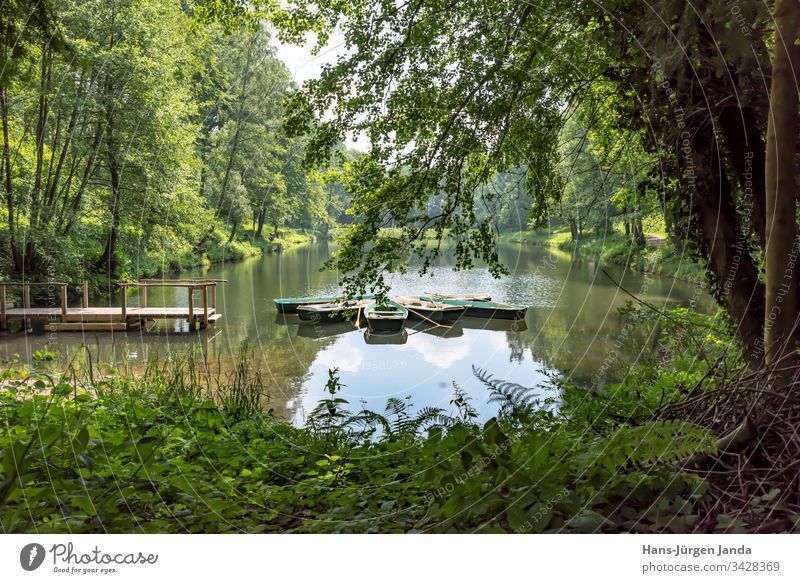 Ruderboote auf einem Bergsee mit Holzsteg in einem bewaldeten Tal bergsee gebirgssee Teich wasser Weiher Boot naherholungsgebiet ruhig entspannung brün nass