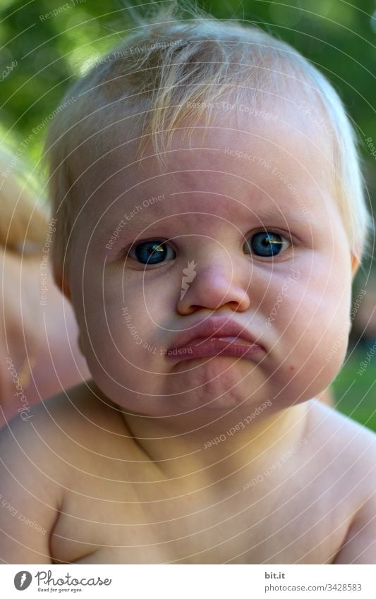 kleines Mädchen in der Natur, verzieht das Gesicht zu einer lustigen Schnute und sieht dabei traurig aus. Baby Kleinkind Kinderspiel Kindererziehung Erziehung