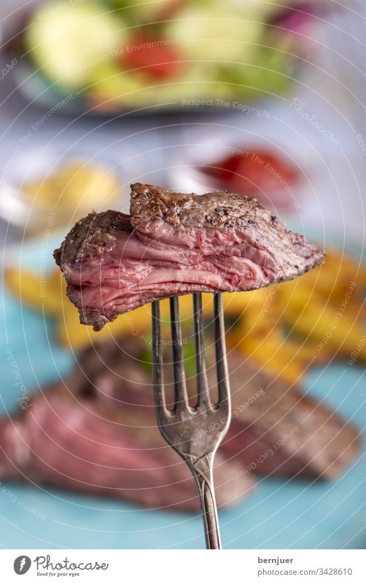 Steak auf einer Gabel Rindfleisch Rindersteak Silbergabel Scheibe Sirloin Braten geröstet Fleisch saftig Stück geschnitten rot Essen medium Hintergrund Teller