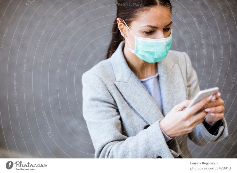Hübsche junge Frau mit schützender Gesichtsmaske auf der Strasse Virus Mundschutz Gesundheit ansteckend Sicherheit Seuche Telefon Krankheit Mobile Coronavirus