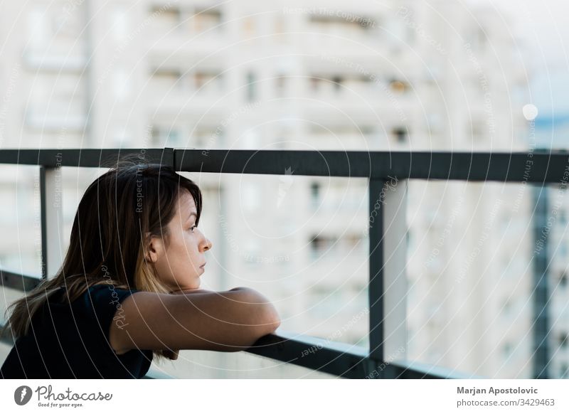 Junge traurige Frau, die durch den Balkon eines Wohnhauses nach draußen schaut Erwachsener allein Angst Appartement Kaukasier Großstadt betroffen Krise