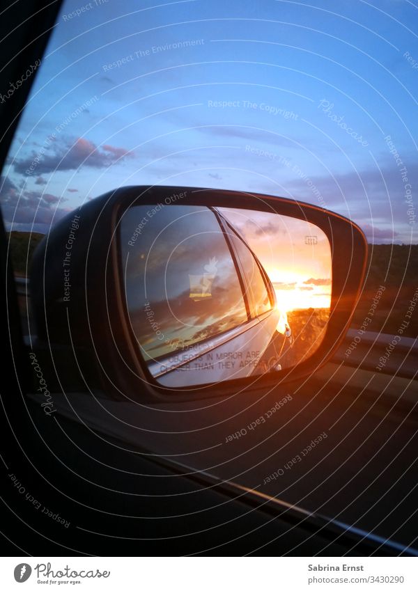 Spiegelung eines Sonnenuntergangs im Außenspiegel Autospiegel spiegeln PKW farbenfroh Licht Verkehr Straße Autobahn reisen Roadtrip Rückblick Panorama