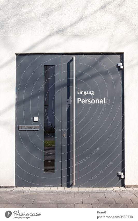 Personaleingang Fassade Wand weiß Gehweg Platten Eingangstür Tür grau Schriftzeichen Türschloss Griff Scharniere Briefkasten Glas Spiegelung Schatten