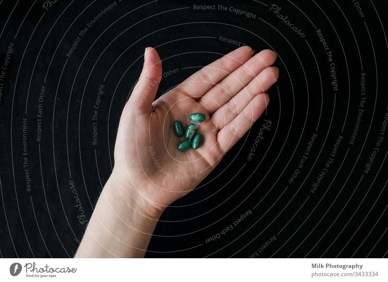 Leuchtend grüne Pillen in einer menschlichen Hand Nahaufnahme Schmerztabletten sortiert Antibiotikum Vitamin Ergänzung Abhilfe Verschreibung Tablette Apotheke