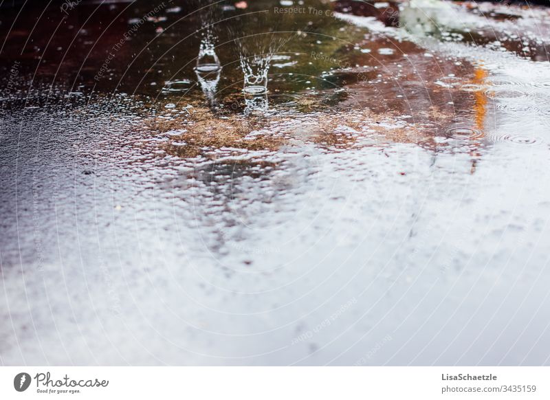 Wassertropfen treffen auf nassen Asphalt auf. Ein regnerischer Tag auf der Straße. regen wasser spiegelung boden beschaffenheit abstrakt wand kalt blau dekor