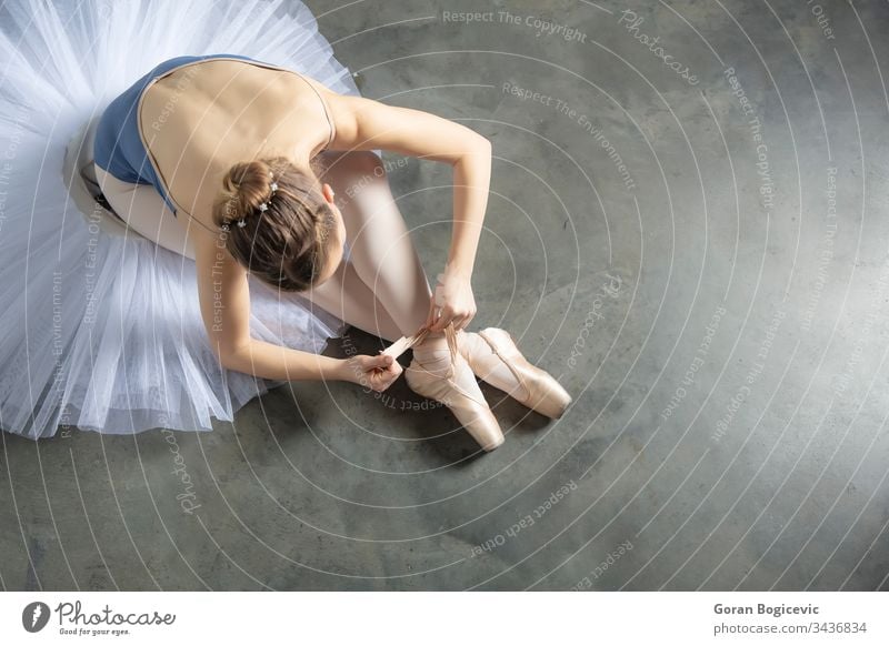 Draufsicht auf eine Balletttänzerin, die sich Hausschuhe um den Knöchel bindet Fußknöchel Künste Ballerina Kaukasier Klassik Tracht Tanzen Eleganz Frau Mädchen