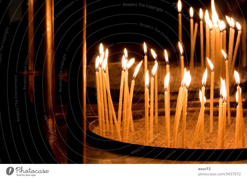Gruppe von gelben Kerzen in der Kirche für das Auferstehungsgebet des Glaubens. Kerzenschein-Feuerflammen in Kreisreihen sind religiöses Symbol für Frieden, Leben und Seelenstille. Nachruf Hoffnungsopfer gegen die Trauer