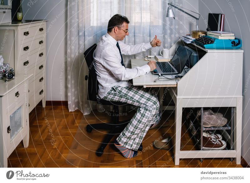 Mann bei der Telearbeit mit Hemd, Krawatte und Pyjamahose von zu Hause aus arbeiten Videoanruf Vereinbarung Coronavirus Seuche Quarantäne covid-19 Business