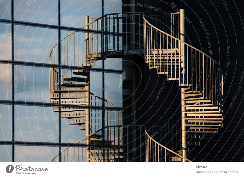 Wendeltreppe in der Abendsonne und in einer Glasfassade gespiegelt Treppe spiegeln Fassade Scheibe Architektur Menschenleer Gebäude Haus Spirale Nottreppe Helix