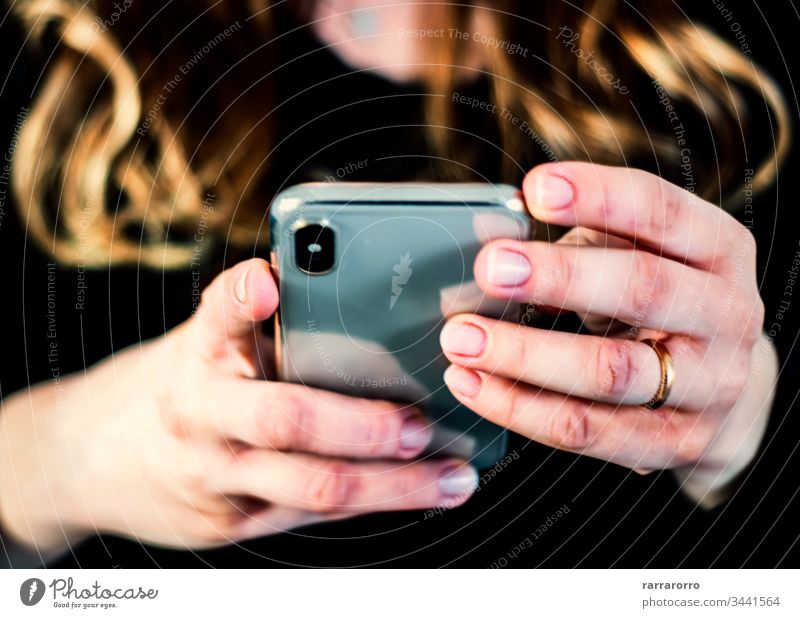 die Hände einer jungen kaukasischen brünetten Frau, während sie ein Smartphone hält, das auf dem Touchscreen tippt. Frauen Handy Beteiligung Menschen