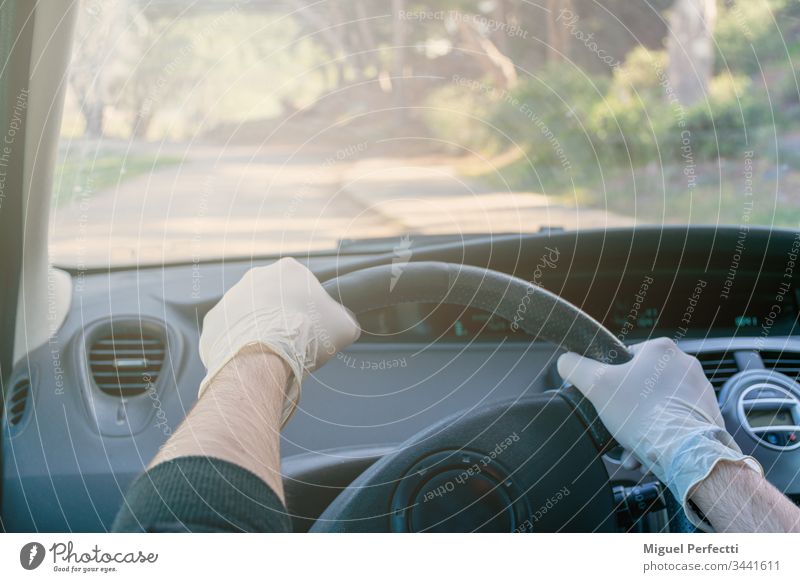 Hände, die das Lenkrad eines Autos während der Fahrt mit Latexhandschuhen halten, um eine Ansteckung zu vermeiden Erwachsener Automobil PKW Autoinnenraum