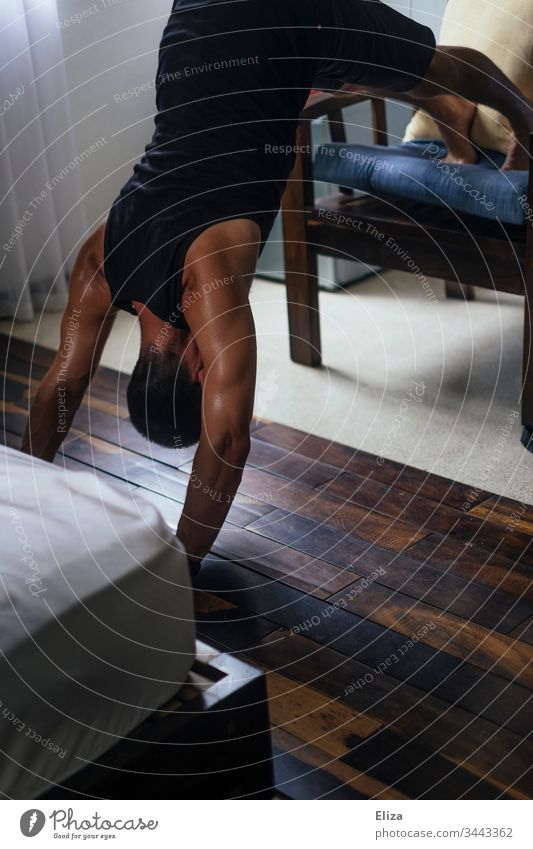 Ein Mann, der Zuhause Sport macht und trainiert um fit zu bleiben Workout Fitness Sport-Training sportlich Junger Mann Gesundheit Muskeln schweiß improvisieren
