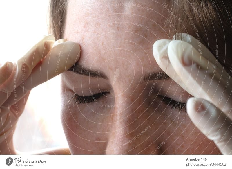 Frau mit Latexhandschuhen blickt durch Coronavirus, Covid-19-Selbstisolierung oder Depression gestresst nach unten - Porträt in Nahaufnahme medizinisch Medizin