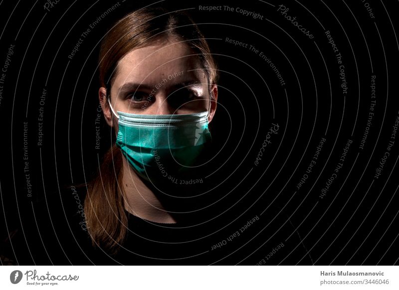 Frau mit medizinischer Maske zum Schutz des Coronavirus covid-19 SARS-CoV-2, Frau mit Maske auf schwarzem Hintergrund 30s Erwachsener apokalyptisch