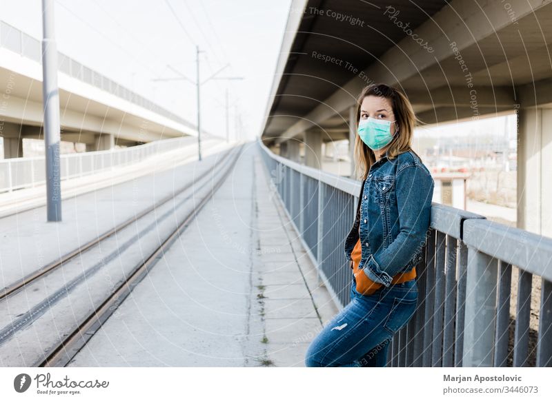 Junge Frau mit einer chirurgischen Maske in einer leeren Straßenbahnhaltestelle allein Biogefährdung Pflege Kaukasier Großstadt Ansteckung Coronavirus covid-19