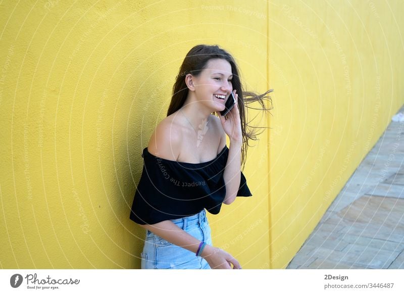 Hübsches Mädchen an gelber Wand lehnt, junge freundliche Frau lächelt glücklich an einem sonnigen Sommertag 1 Person Erwachsener attraktiv Glück Hintergrund