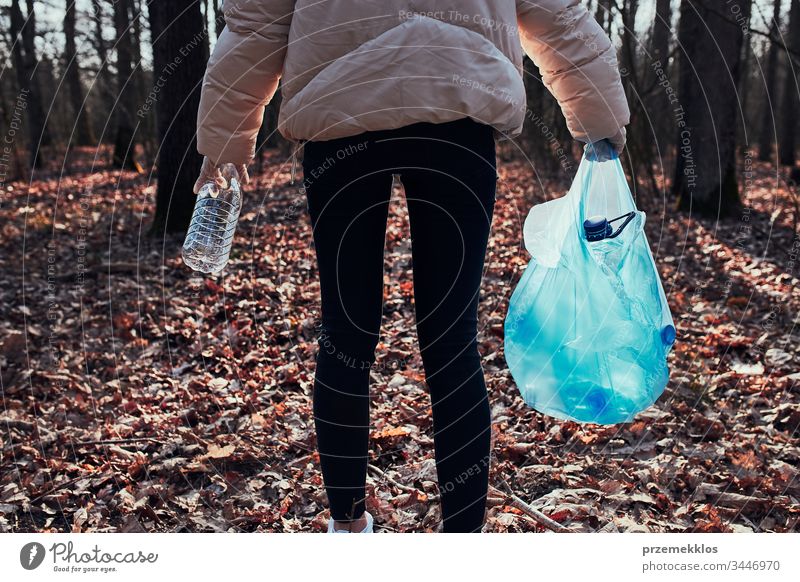 Junge Frau räumt einen Wald auf. Freiwillige Helferin beim Einsammeln von Plastikmüll in Säcke. Konzept der Plastikbelastung und zu viel Plastikabfall. Umweltproblematik. Umweltschäden. Verantwortung für die Umwelt. Echte Menschen, authentische Situationen