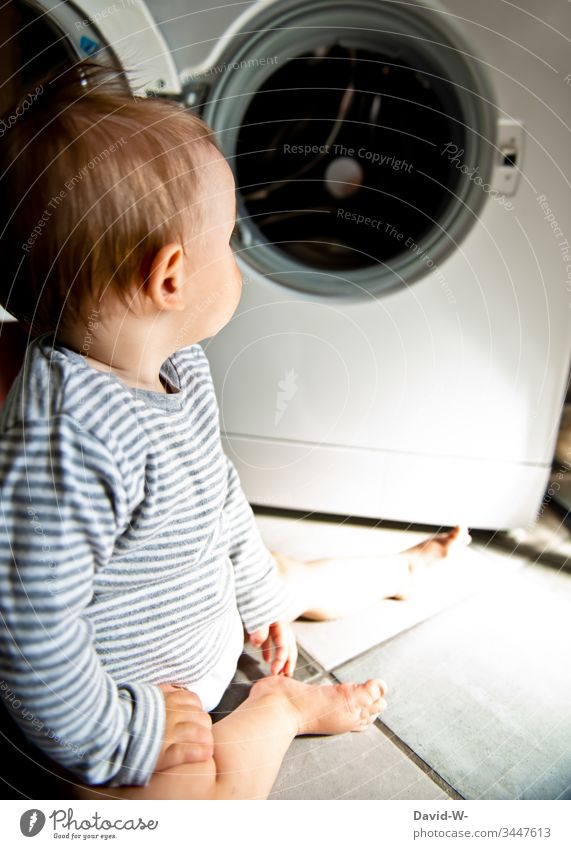 Baby Kleinkind sitzt interessiert und neugierig vor Waschmaschine auf dem Boden niedlich Kind Gefahr beobachten neugierde Junge Verantwortung erkunden erkundend