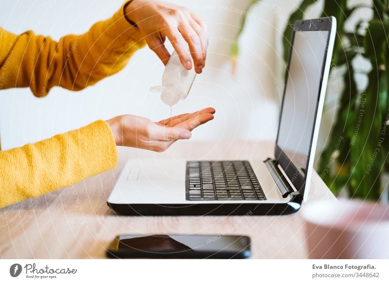 junge Frau, die zu Hause am Laptop arbeitet und Handdesinfektionsmittel Alkoholgel verwendet. Während des Coronavirus covid-2019-Konzepts zu Hause bleiben