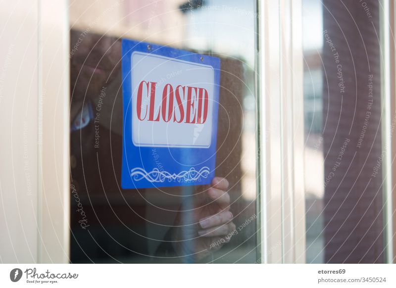 Geschäftsmann hängt geschlossenes Schild für Coronavirus covid-19 Vollbart Vorsicht zugeklappt Krise Tür Mitarbeiter Unternehmer Seuche Glas erhängen Mann