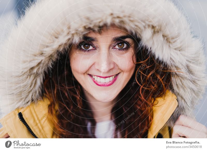 Porträt einer jungen schönen Frau mit Kapuze, die im Freien lächelt. Fröhlichkeit und Lebensstil Lächeln gelb Mantel Großstadt urban Straße Glück Kaukasier