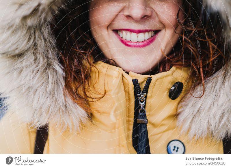 Porträt einer jungen schönen Frau mit Kapuze, die im Freien lächelt. Fröhlichkeit und Lebensstil unkenntlich Lächeln gelb Mantel Großstadt urban Straße Glück