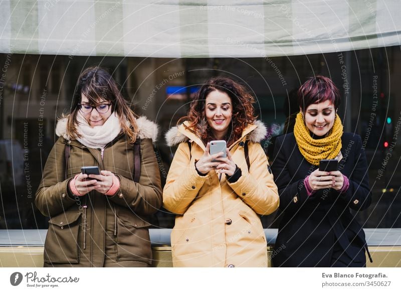 eine Gruppe von Freunden, die draußen auf der Straße ein Mobiltelefon benutzen. Glückliche Frauen, die lächeln. lebensstil und reisekonzept Menschengruppe