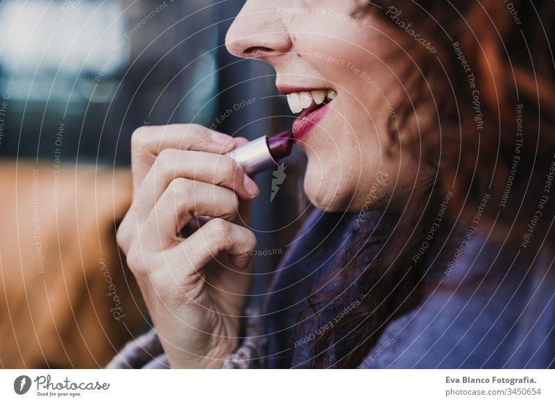 Porträt einer jungen schönen Frau, die draußen auf einer Terrasse roten Lippenstift benutzt. Make-up und Lifestyle-Konzept zusammenstellen Handy Lächeln
