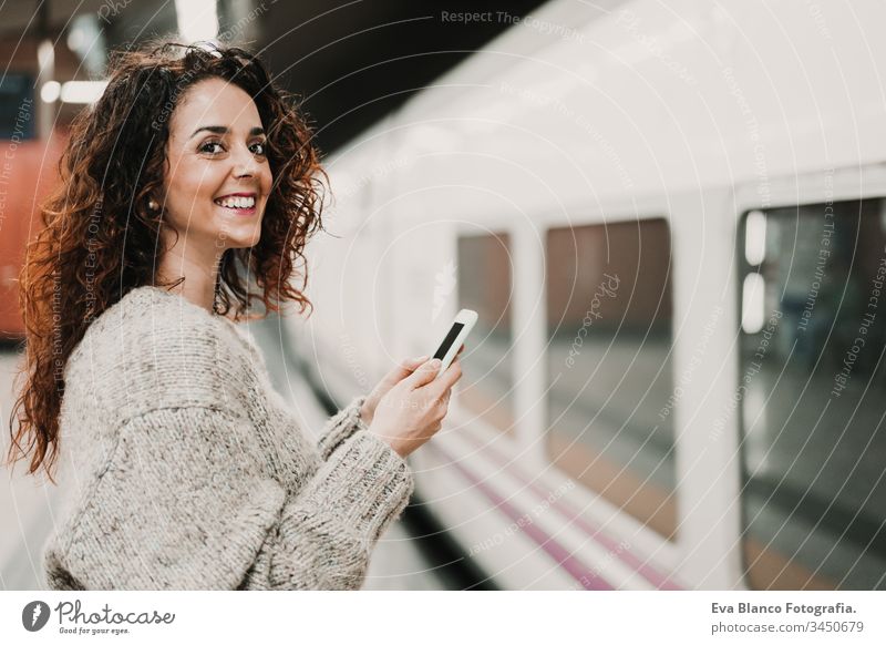 junge, schöne Frau am Bahnhof mit dem Handy, bevor sie den Zug erreicht. Reise-, Technologie- und Lifestyle-Konzept reisen Station bewegend Kaukasier Madrid