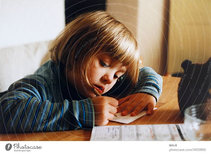 Kleines Mädchen sitzt zuhause am Tisch in der Sonne und malt und lernt schreiben für die Schule. Wohnung Bleibt daheim Bleibt zuhause drinnen Stimmung Gefühle