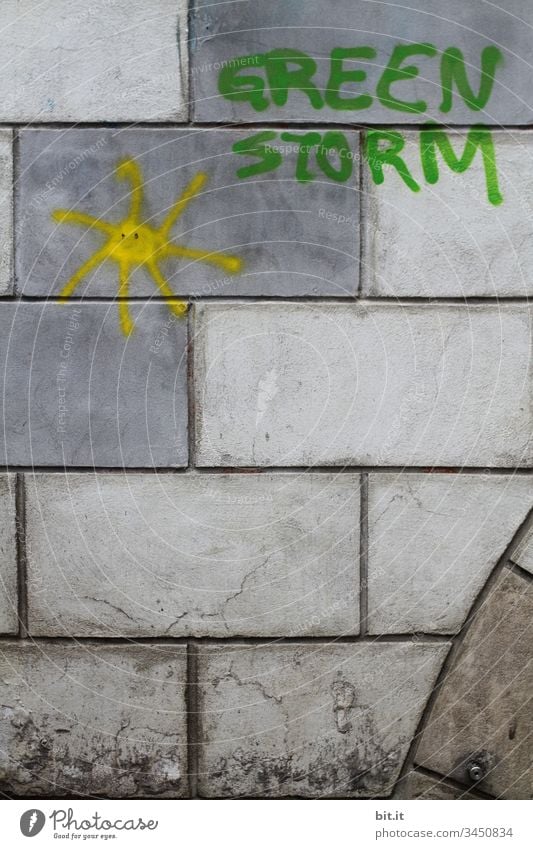 Green Storm mit Sonne als Schriftzug und Icon auf eine graue Mauer mit Mauersteinen gesprayt. Klimawandel green Greenstorm Sturm grün Wand Fassade Graffiti