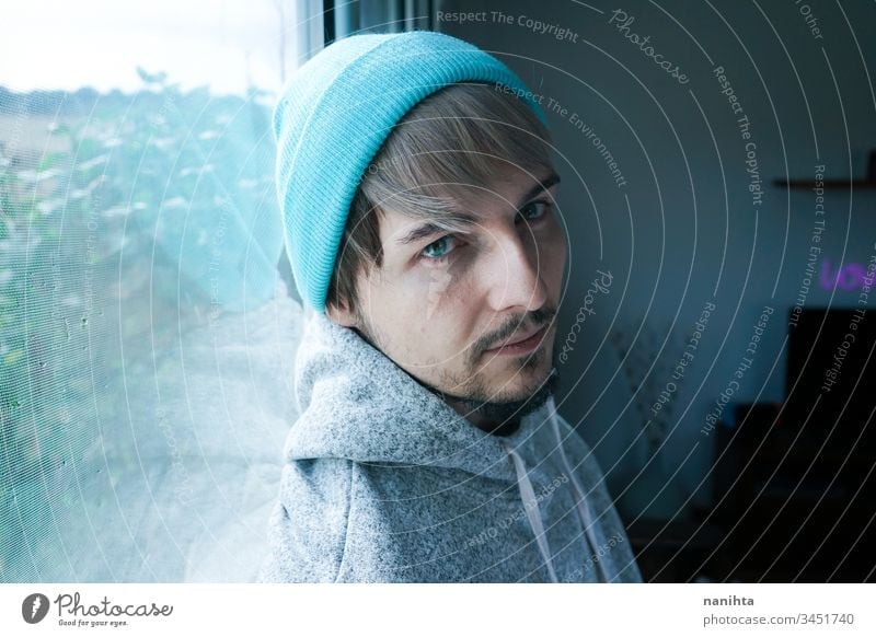 Junger Mann allein zu Hause in der Nähe eines Fensters männlich Porträt vereinzelt heimwärts gesperrt Quarantäne einsam Selbst attraktiv gutaussehend Typ lässig
