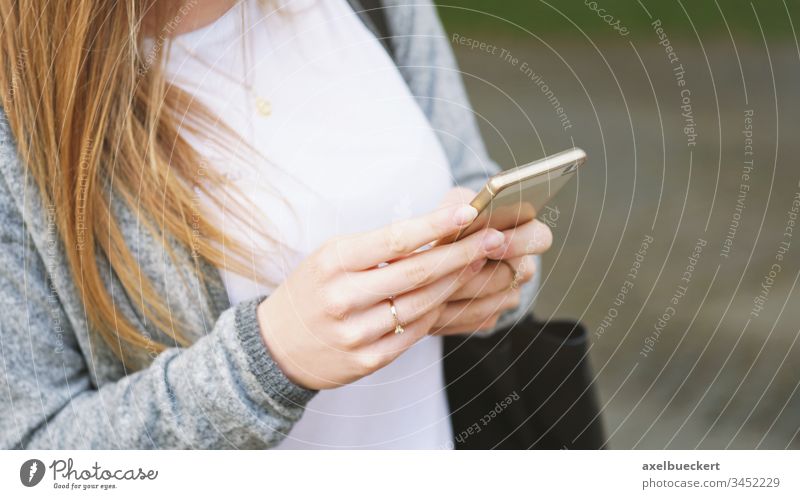 nicht erkennbare junge Frau, die ein Smartphone im Freien benutzt benutzend Mobile Telefon Funktelefon Zelle Mädchen Internet Person wirklich Menschen