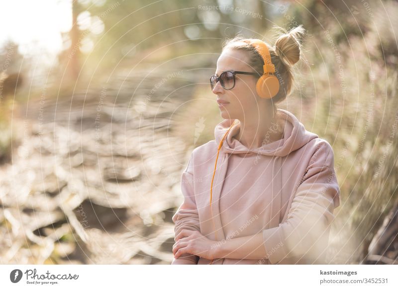 Porträt einer schönen Sportlerin mit Sonnenbrille, Kapuzenpulli und Kopfhörer beim Training im Freien Frau Mädchen Natur aktiv Läufer Sportbekleidung jung