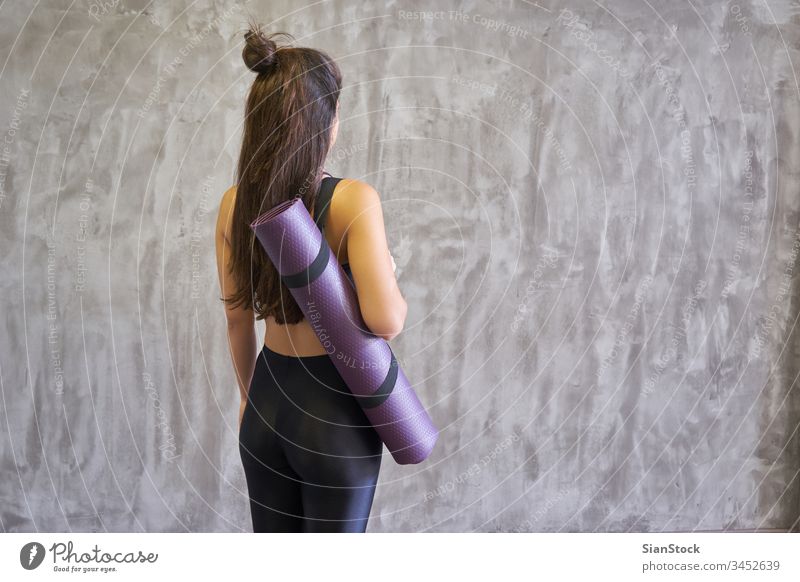 Frau in einem Yogastudio im Haus, die eine Matte hält. Atelier jung Übung Fitness Pose schön Training Körper Person Gesundheit Meditation Hintergrund