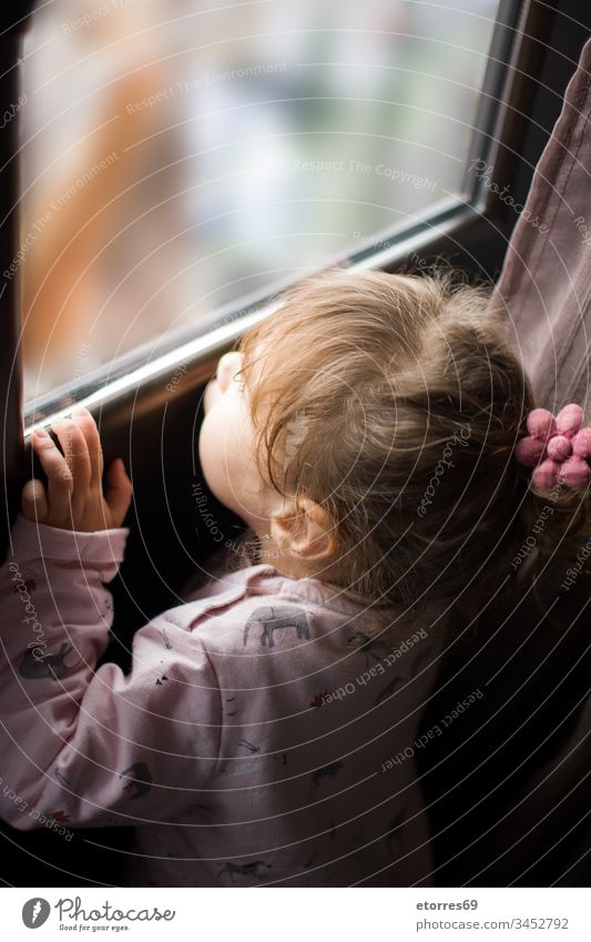 kleines Mädchen, das aus dem Fenster schaut Baby blond Kaukasier Konzept Coronavirus covid.19 Grippe heimwärts Haus Kind wenig Blick Aus im Freien Person