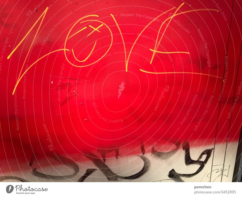 Graffiti gelbe Schrift auf rotem Untergrund englisches Wort love, smiley und schwarzes Geschmiere Smiley subkultur geschmiere jugendkultur illegal verboten