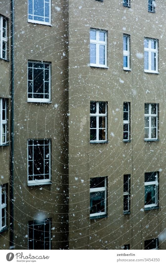 Schneefall vor leeren Fenstern altbau außen fassade fenster haus hinterhaus hinterhof innenhof innenstadt mauer mehrfamilienhaus menschenleer mietshaus schnee