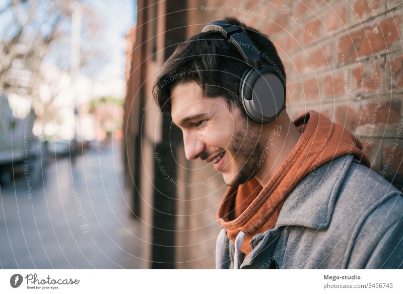 Lateinamerikaner, der mit Kopfhörern Musik hört. Person jung zuhören Menschen Erwachsener Apparatur im Freien Technik & Technologie Lifestyle männlich lässig