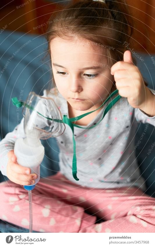 Krankes kleines Mädchen, das eine medizinische Inhalationsbehandlung mit einem Vernebler erhält. Kind mit Atemmaske im Bett sitzend Virus Infektion Arzt Grippe