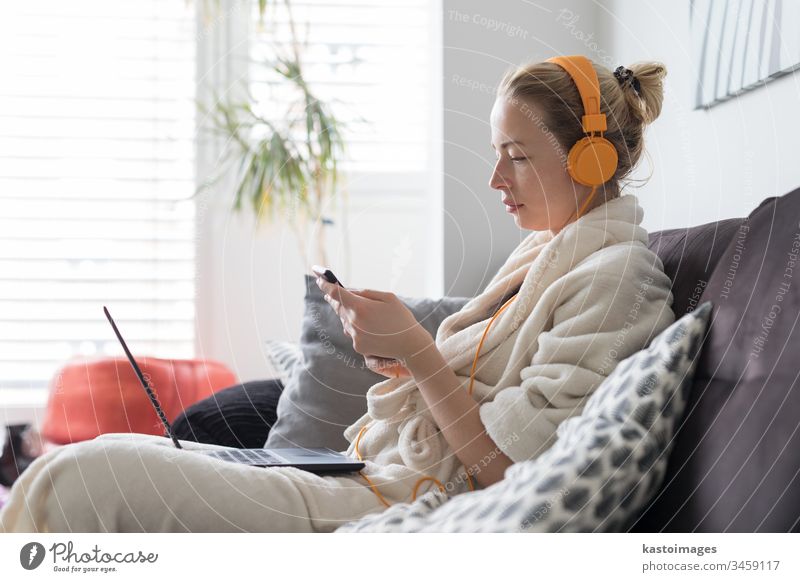 Soziale Distanzierung. Bleiben Sie zu Hause. Frau im Bademantel, die es sich auf ihrem Sofa zu Hause gemütlich macht und Social-Media-Anwendungen am Telefon für Video-Chats und Styling mit ihren Lieben nutzt.