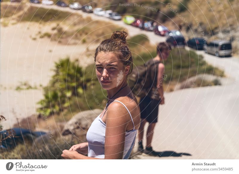 junge Frau, die eine Straße entlanggeht, blickt zurück Rücken Rucksack Strand schön verschwommen Autos lässig Kaukasier Mädchen gutaussehend heiß Reise