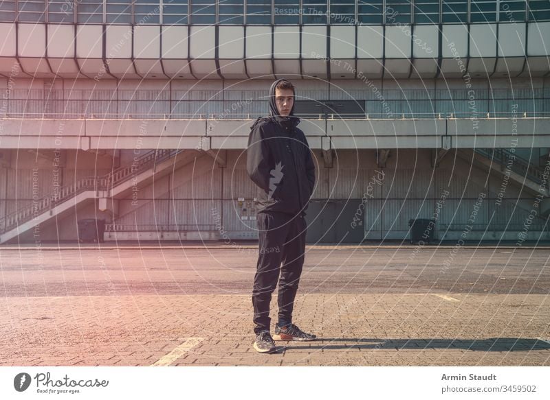 Porträt eines jungen Mannes mit schwarzem Kapuzenpulli Architektur schön Junge Gebäude lässig selbstbewusst Lifestyle Blick männlich Model im Freien Ort