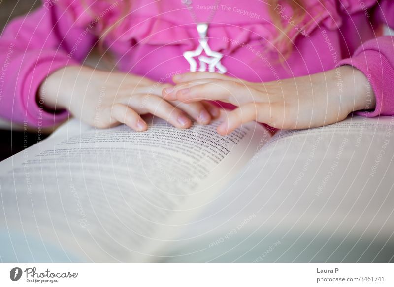 Nahaufnahme der Hände eines kleinen Mädchens beim Lesen bezaubernd achtsam aufmerksam schön blond Buch gelangweilt Kaukasier Kind Kindheit clever konzentriert