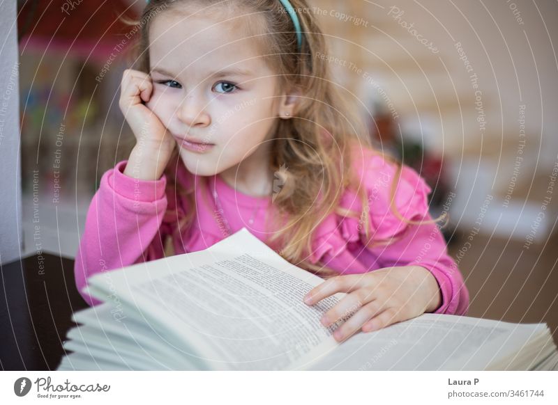Kleines blondes Mädchen müde und gelangweilt vom Lesen und Hausaufgaben machen bezaubernd achtsam aufmerksam schön Buch Kaukasier Kind Kindheit clever